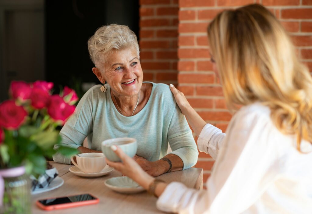 Adult daughter and her mother drinking tea and chatting